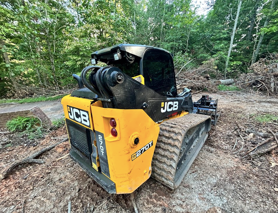 A yellow and black jcb skid steer is parked in a dirt field.