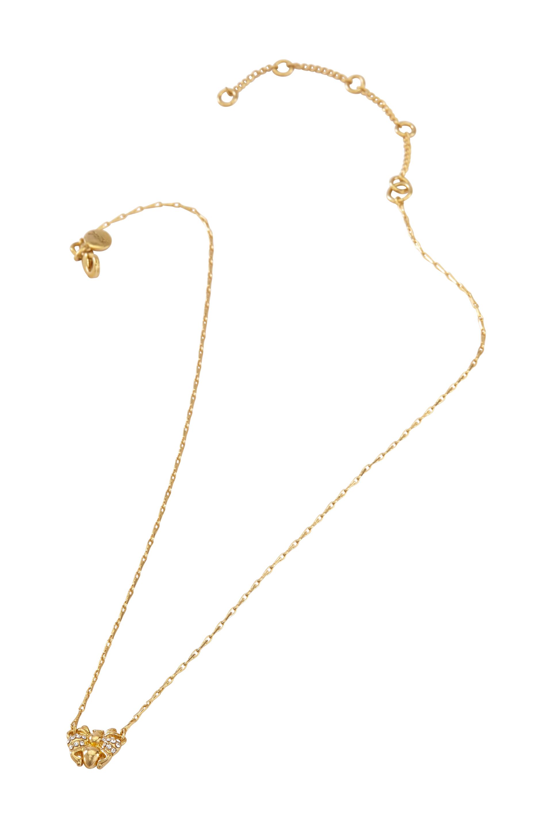 A gold necklace with a heart shaped pendant on a white background