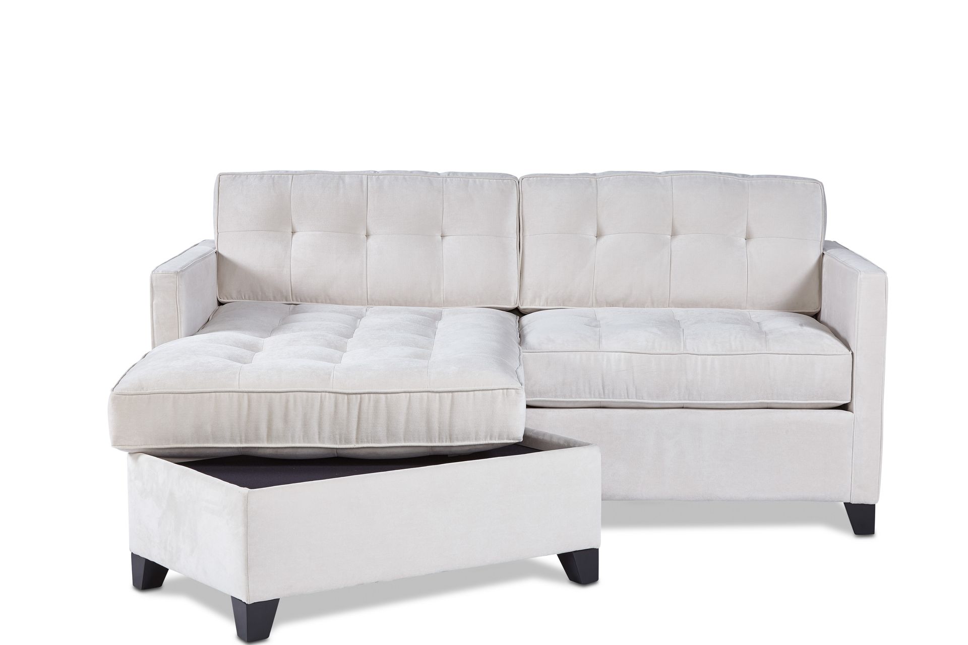 A white sectional couch with an ottoman underneath it