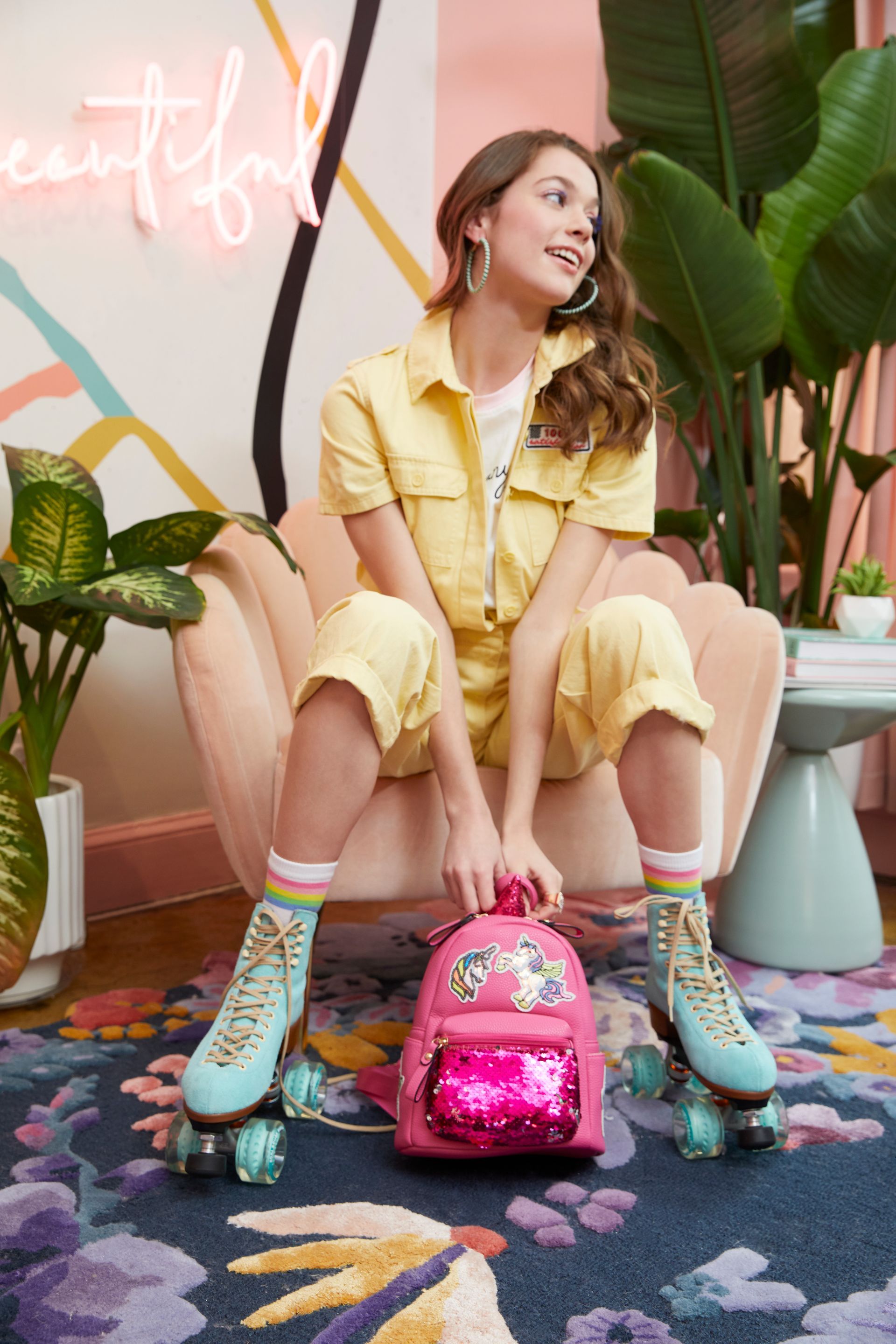 A woman is sitting in a chair holding a pink backpack and roller skates.