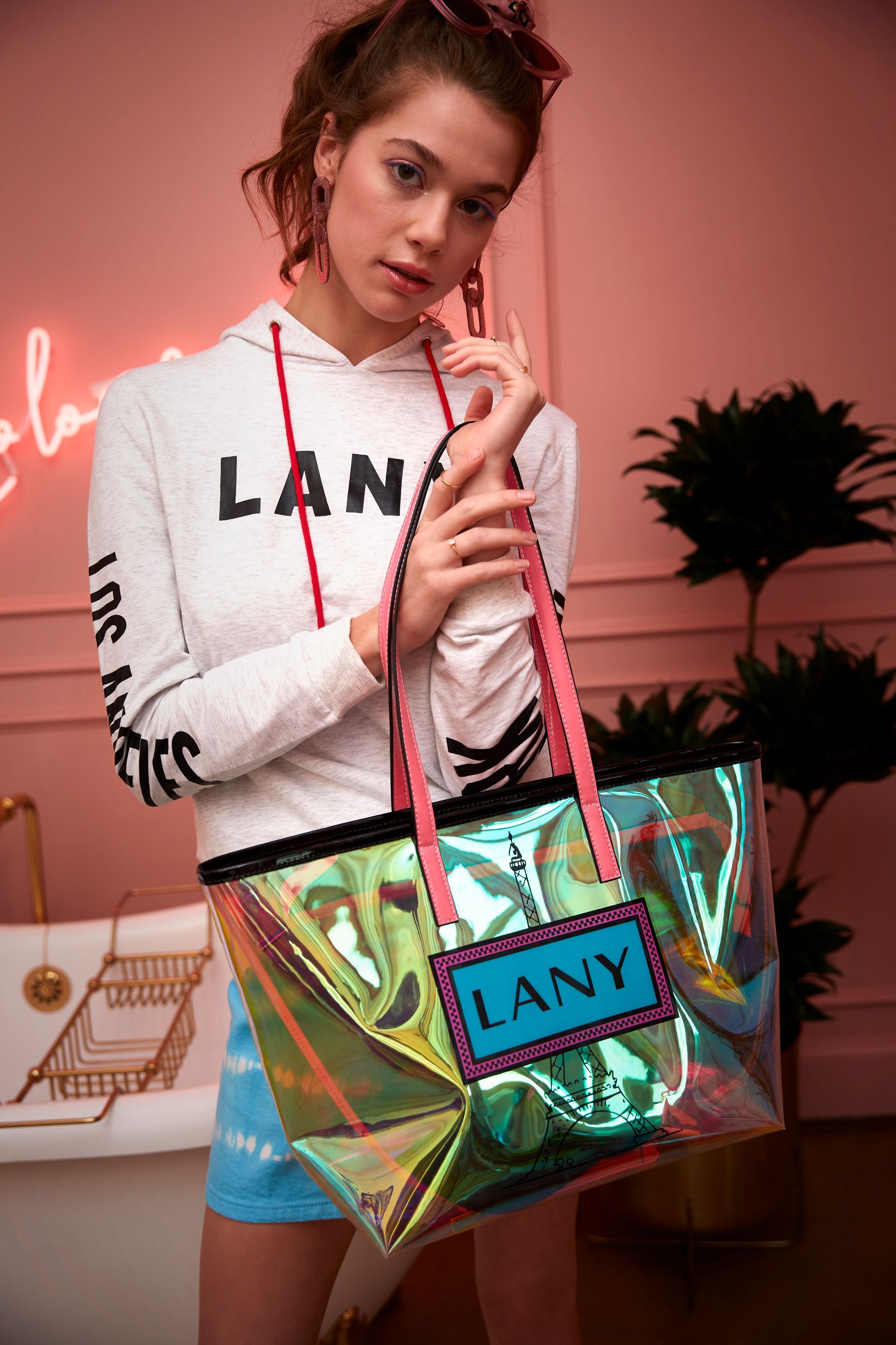 A woman in a hoodie is holding a clear tote bag.