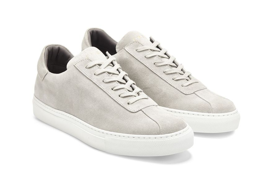 A pair of grey sneakers with white laces on a white background.