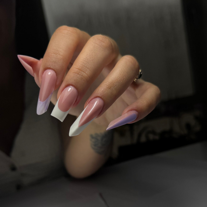 Hand with long, pink and white french tip coffin-shaped nails. One nail has a lavender tip.