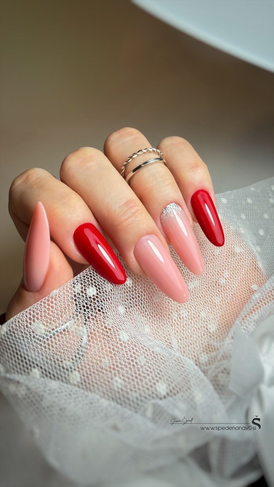 Hand with long, black and nude-colored coffin-shaped nails, on a white surface.