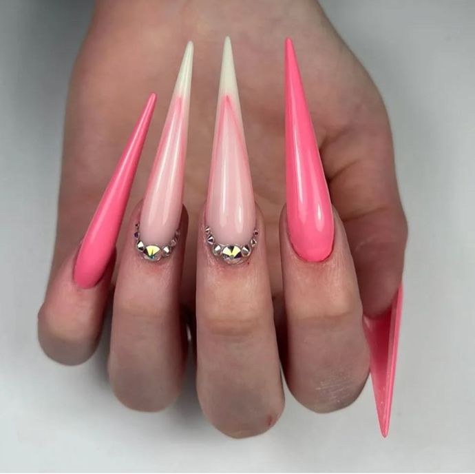 Hand with long, pointed acrylic nails. Pink and white tips, bedazzled accents.