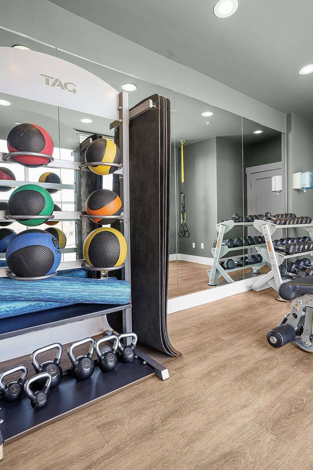 Resident gym interior with kettlebells, medicine balls, mats, and a mirrored wall.