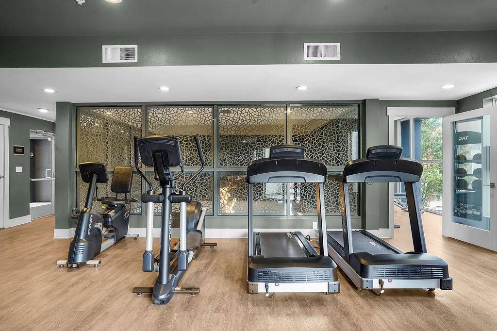 Gym area with treadmills and a stationary bike in a modern apartment community fitness center.