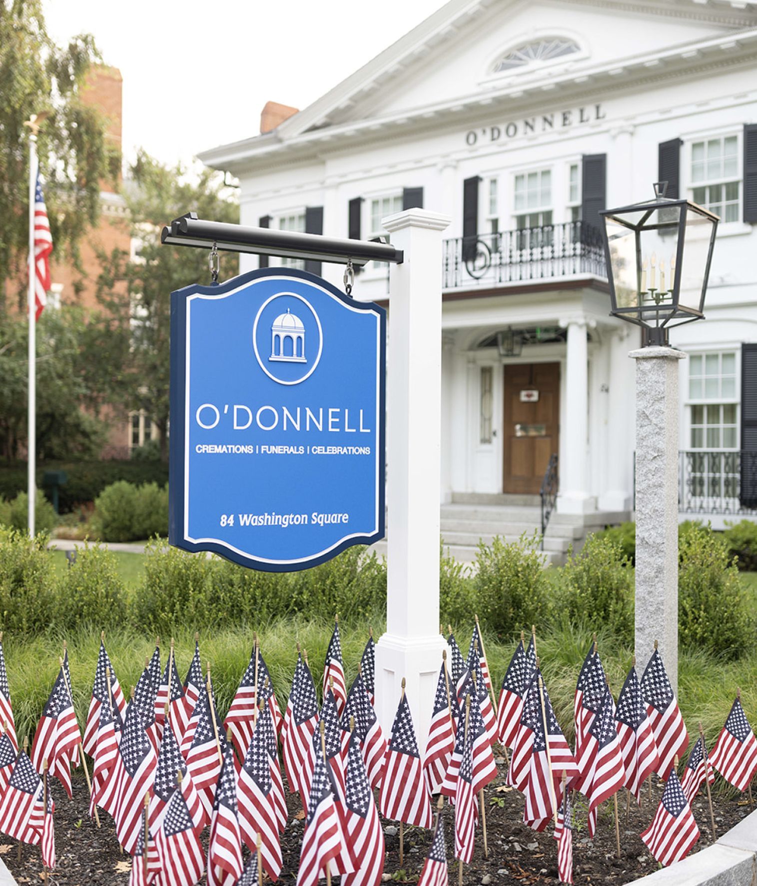 Blue sign for O'Donnell Funeral Home in front of a white building with American flags.