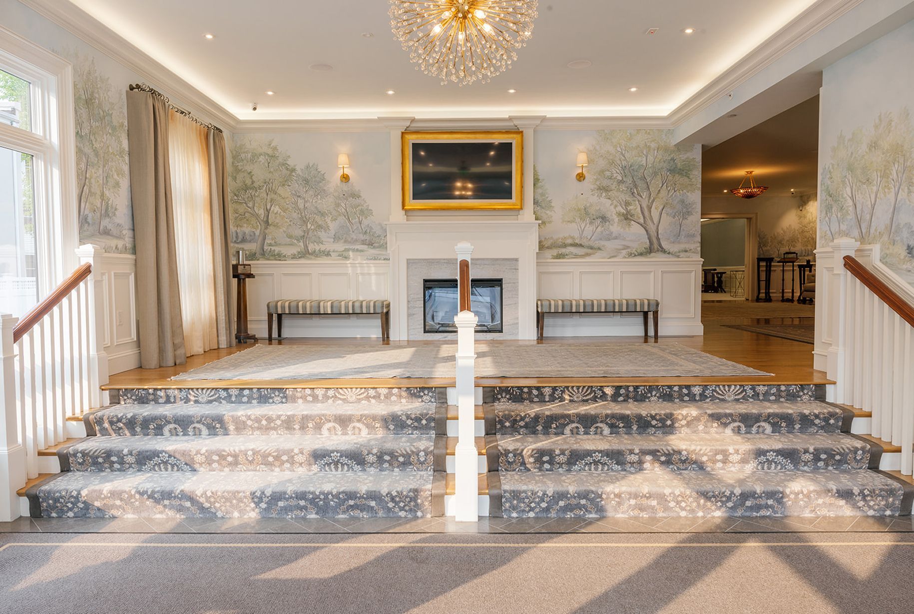 Grand entrance with staircase, light-colored walls, and a fireplace with artwork.