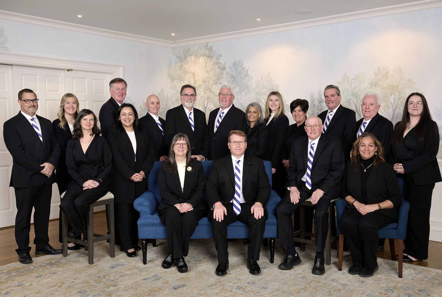 Group of people in business attire posing indoors for a group photo.