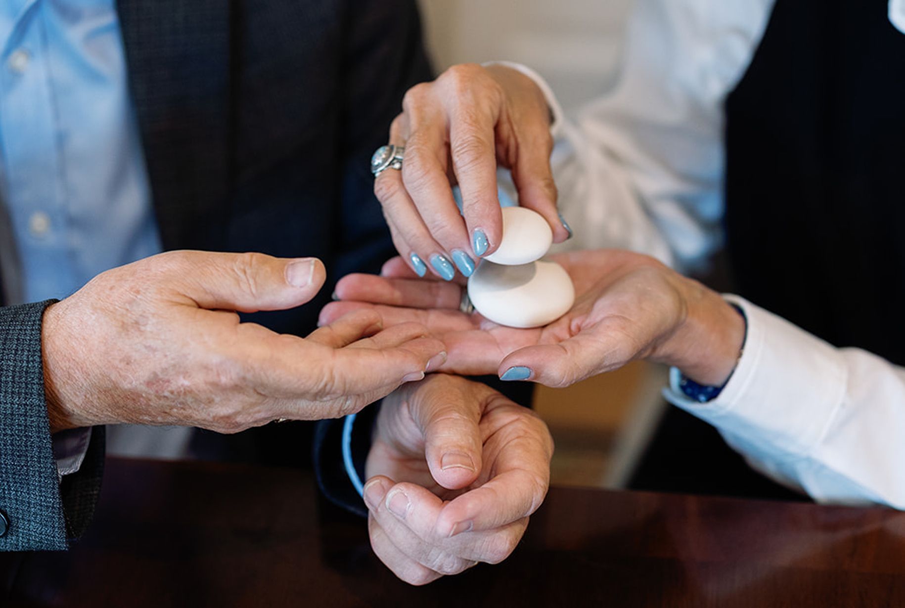Hands holding and passing two white, round objects.