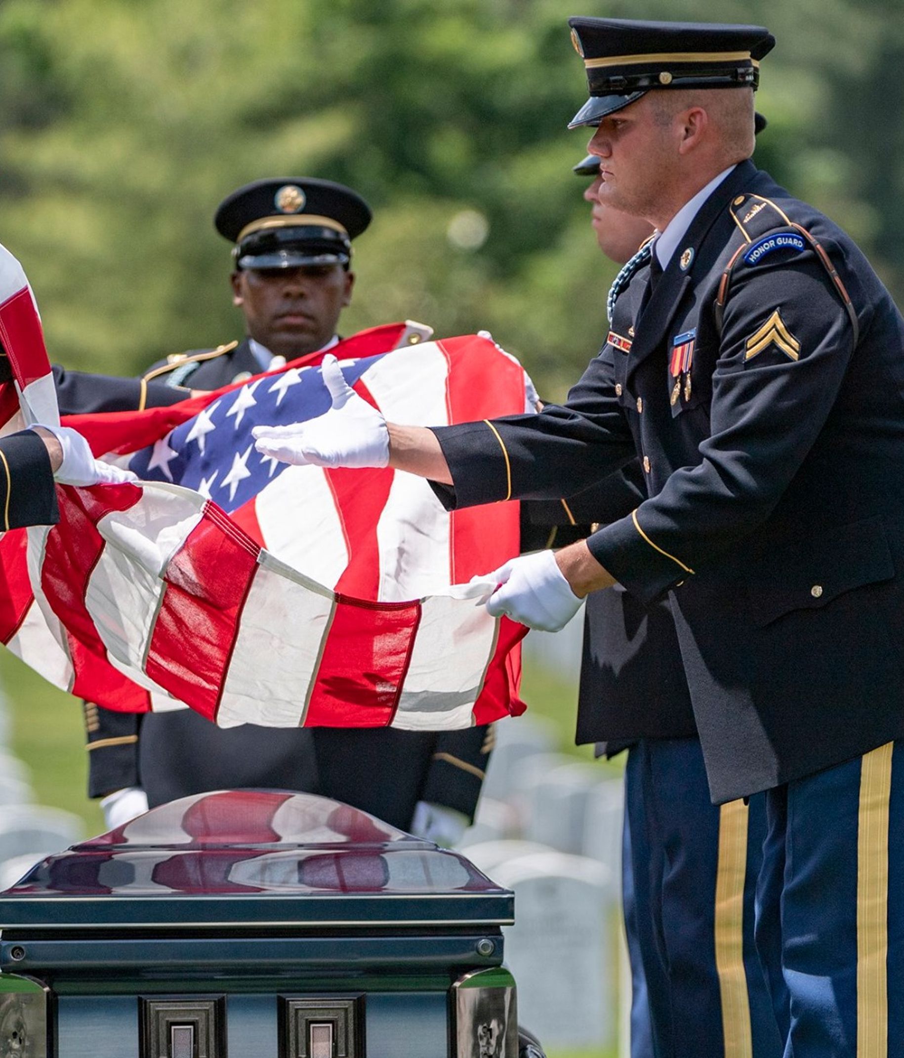 Soldiers folding American flag over a casket at a graveside service.