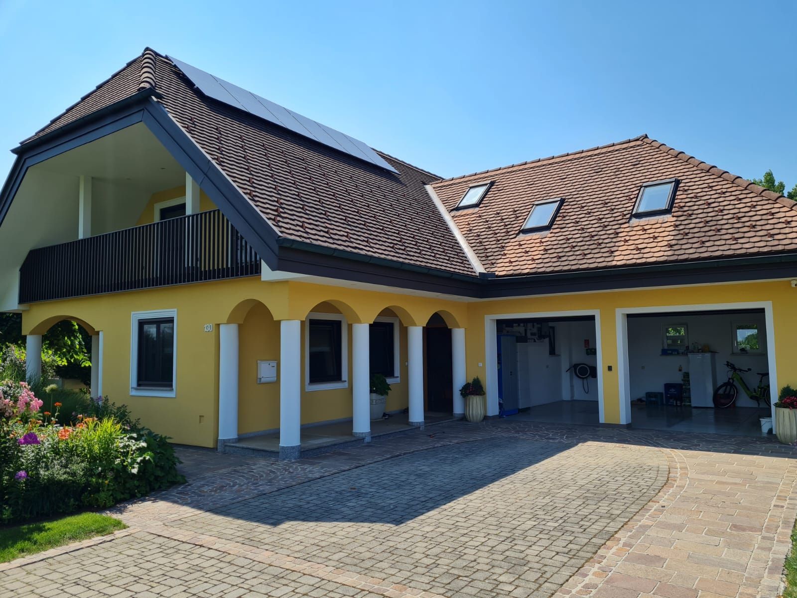 Ein großes gelbes Haus mit einem braunen Dach und einer Garage