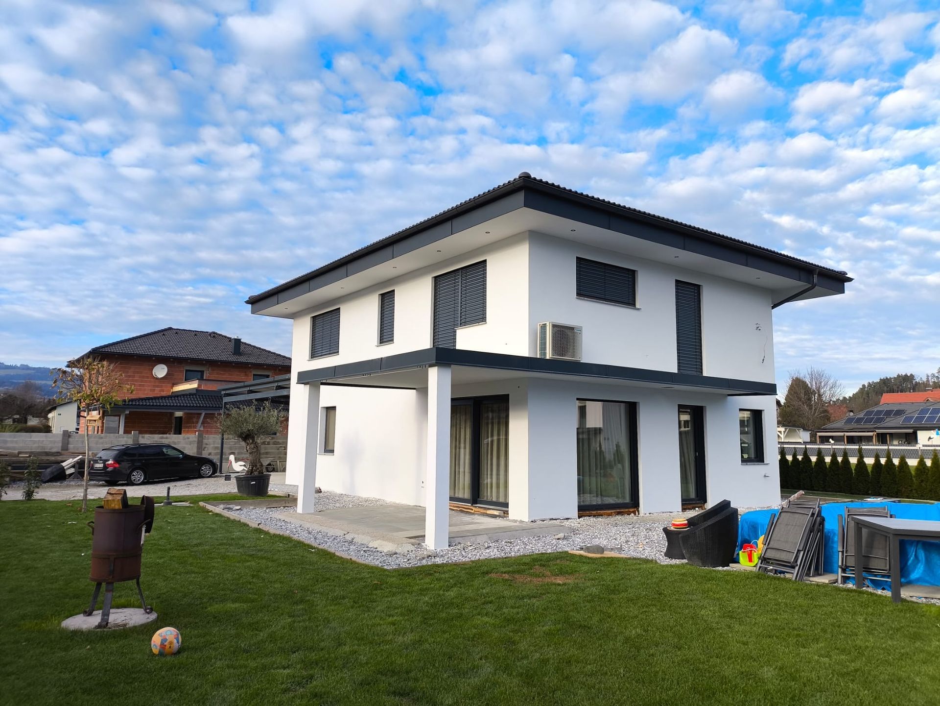 Ein weißes Haus mit schwarzem Dach steht auf einem üppigen grünen Rasen.