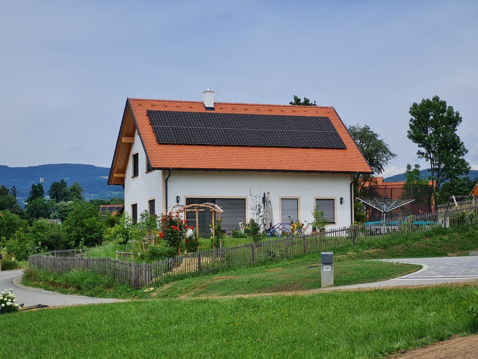 Ein weißes Haus mit einem roten Ziegeldach und Solarzellen auf dem Dach.