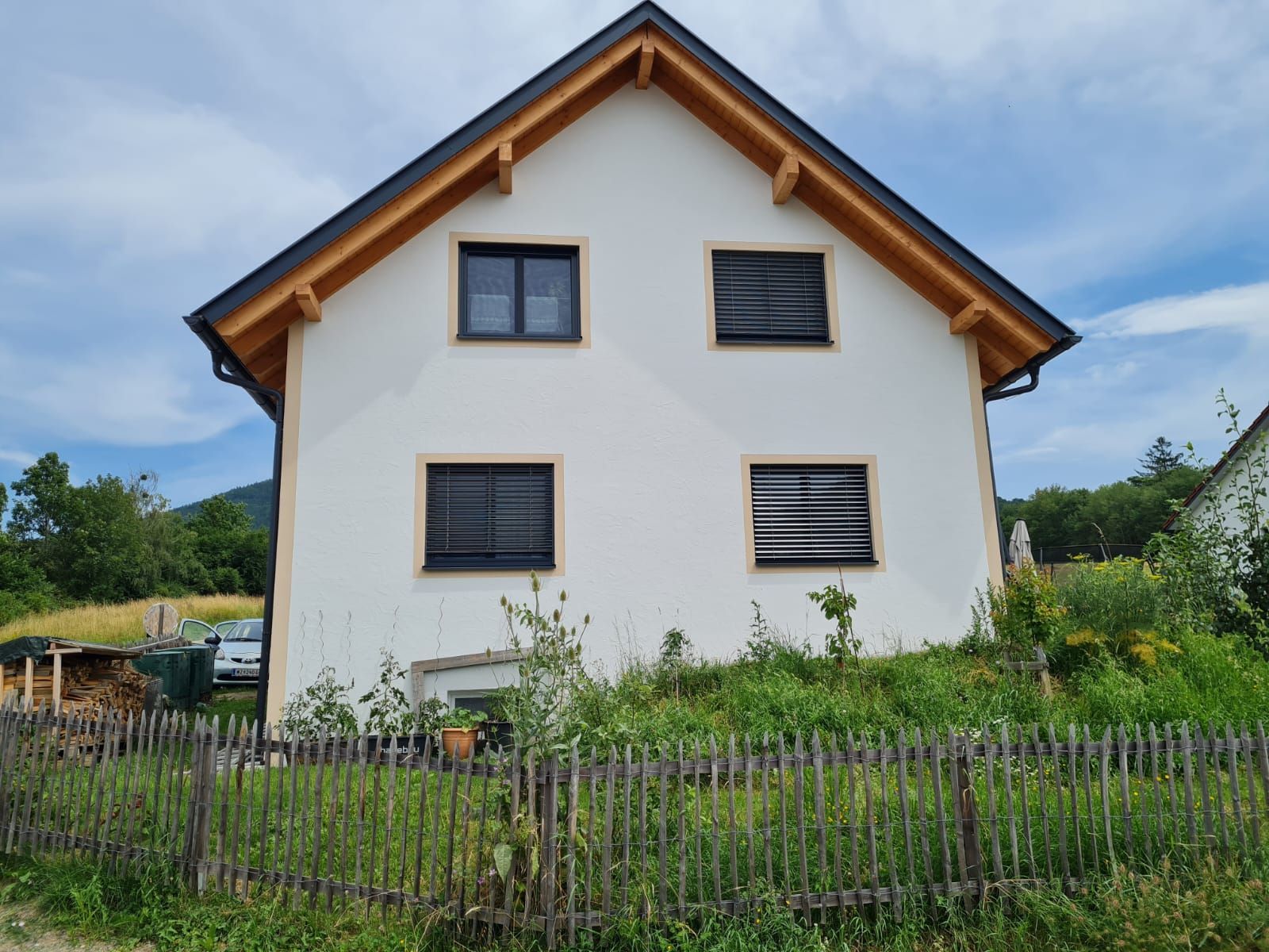 Ein weißes Haus mit einem Holzdach und einem Holzzaun davor