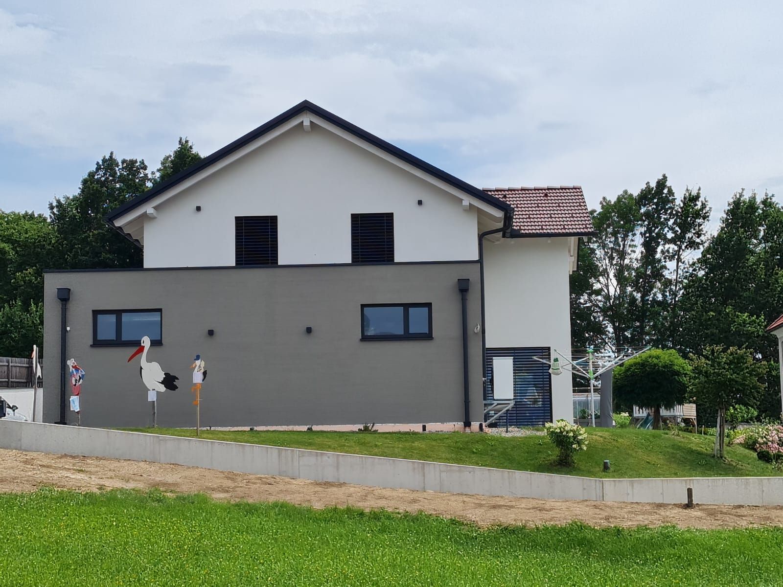 Auf einem grasbewachsenen Hügel steht ein großes Haus mit vielen Fenstern.