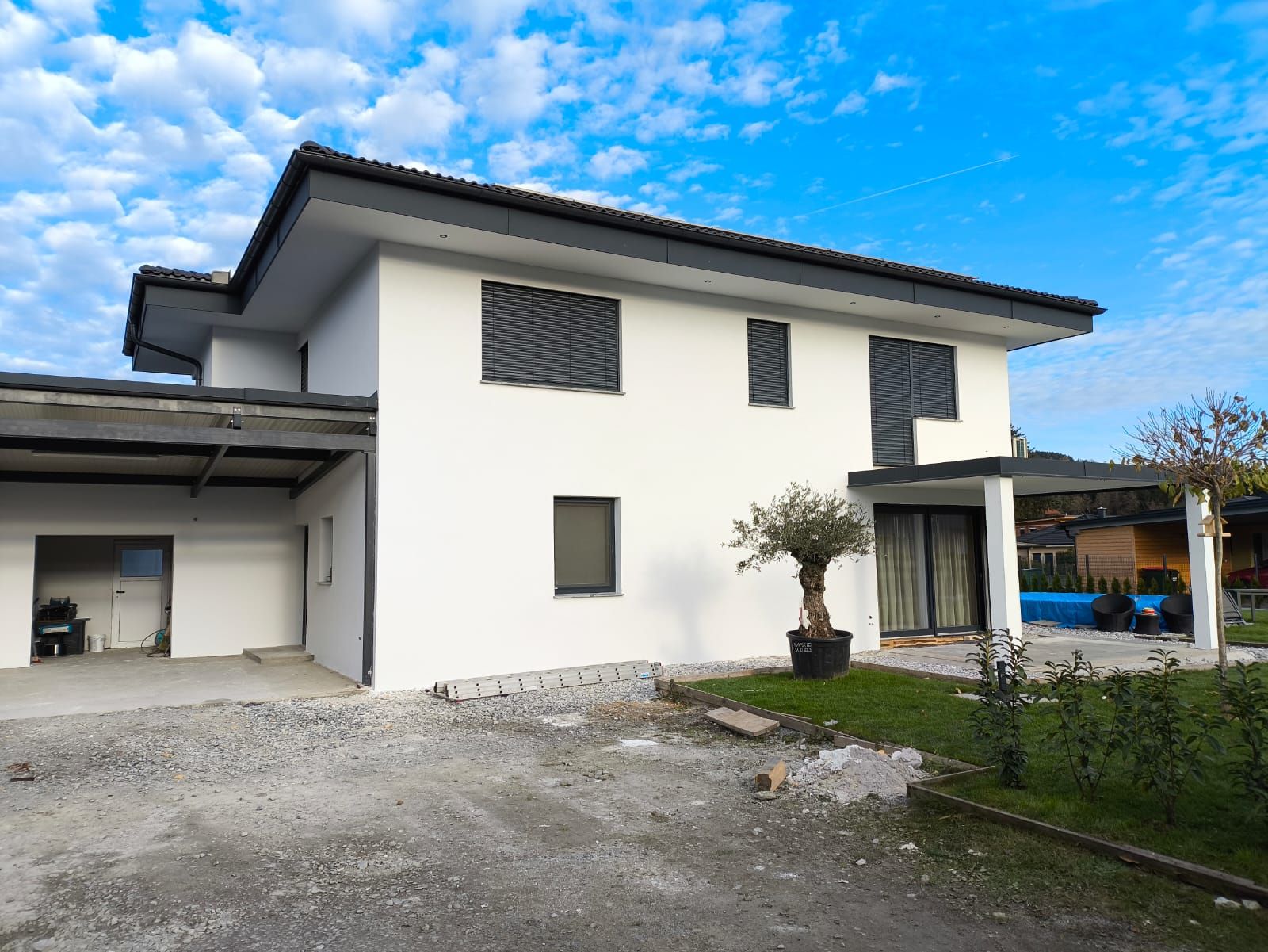 Ein weißes Haus mit einer Garage und einem Baum davor