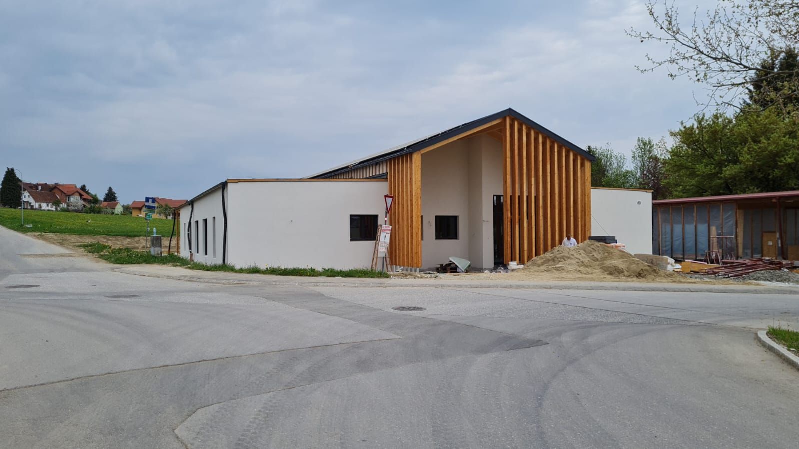 Am Straßenrand wird ein weißes Gebäude mit Holzdach errichtet.