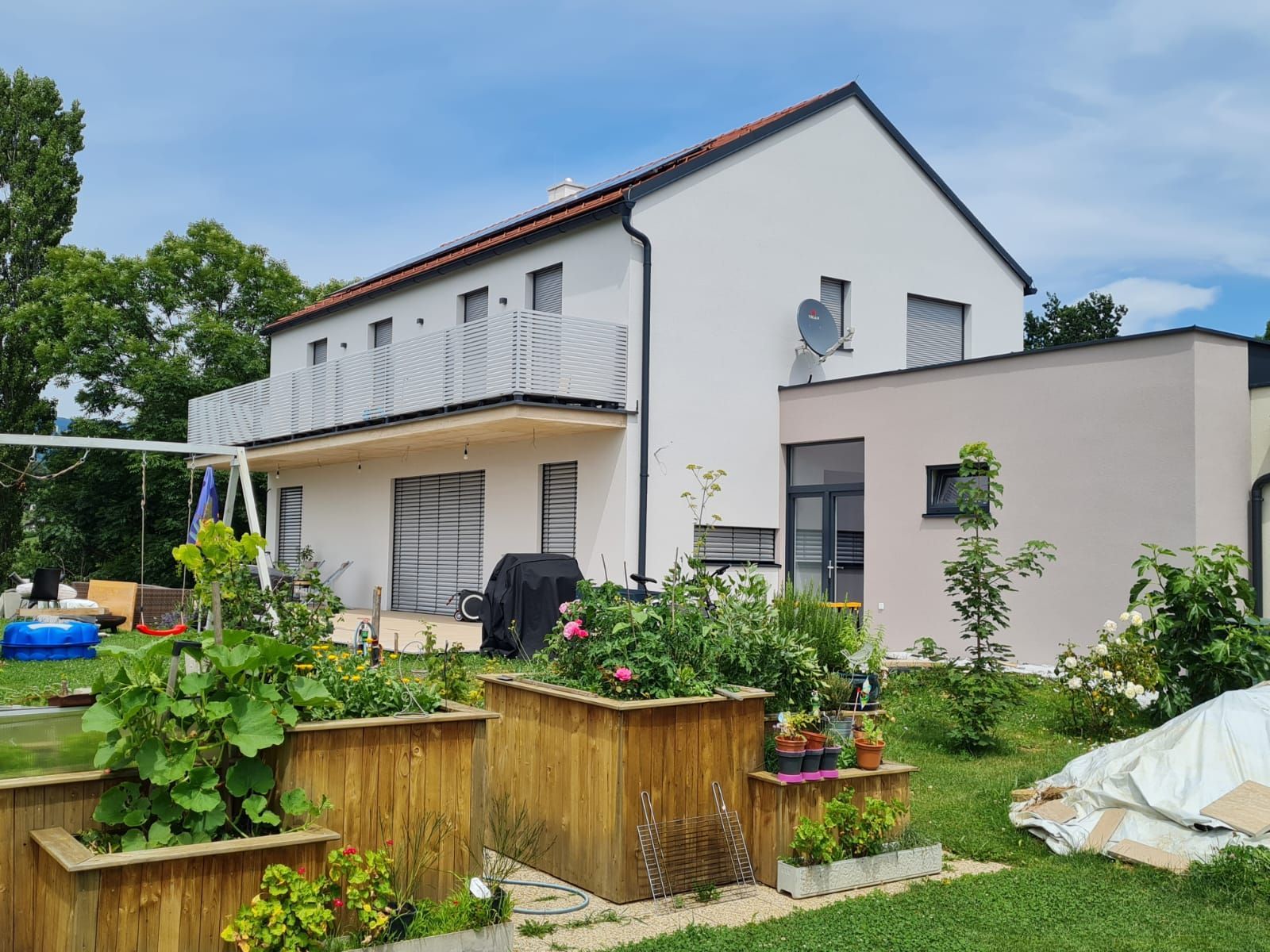 Ein großes weißes Haus mit vielen Pflanzen davor.