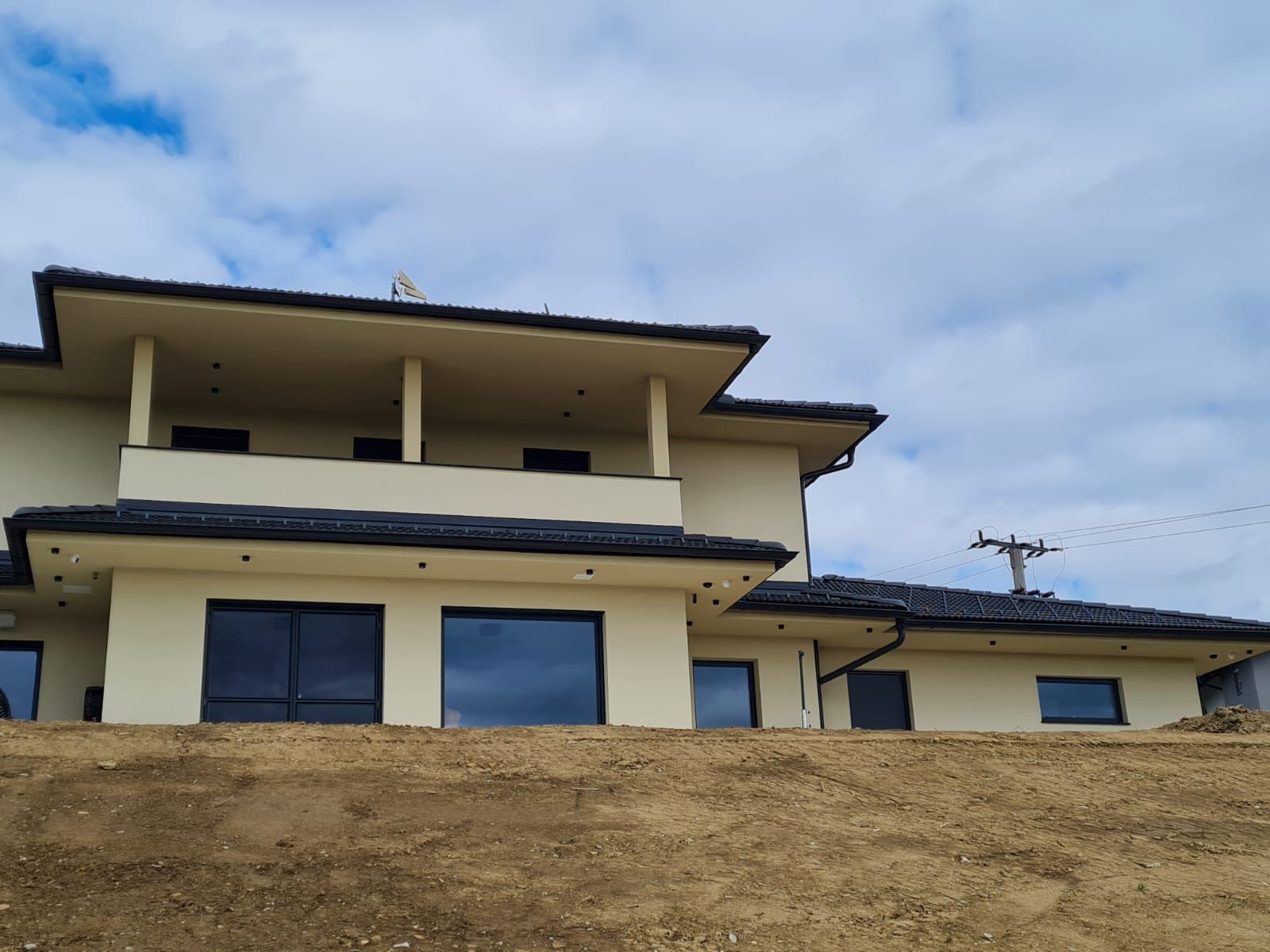 Auf einem Erdhügel steht ein großes weißes Haus.