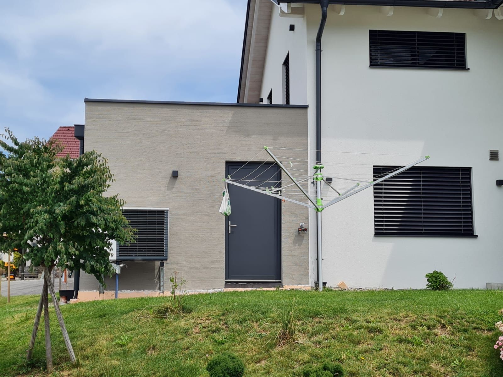 Auf einem grasbewachsenen Hügel steht ein weißes Haus mit einer schwarzen Tür.