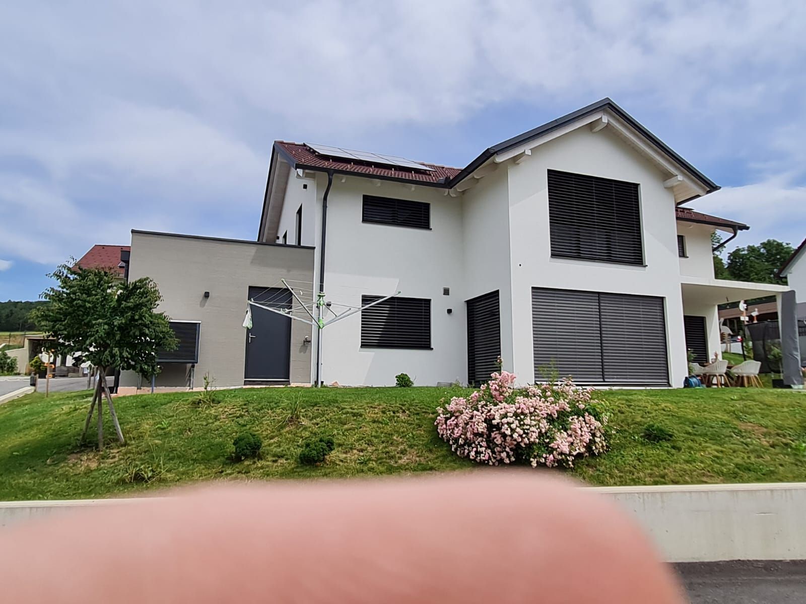 Auf einem grasbewachsenen Hügel steht ein großes weißes Haus.