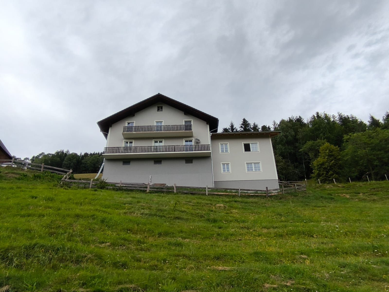 Auf einem grasbewachsenen Hügel steht ein großes weißes Haus.