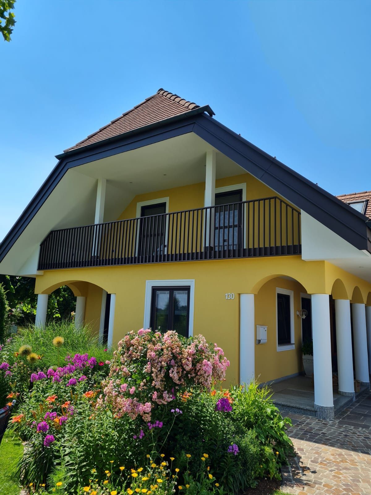 Ein gelbes Haus mit einem Balkon und Blumen davor