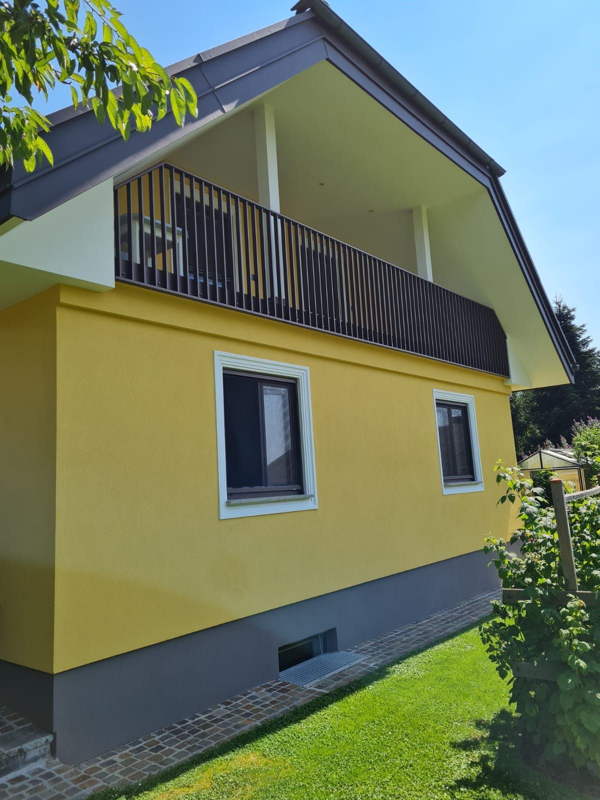 Ein gelbes Haus mit einem Balkon und einem schwarzen Geländer