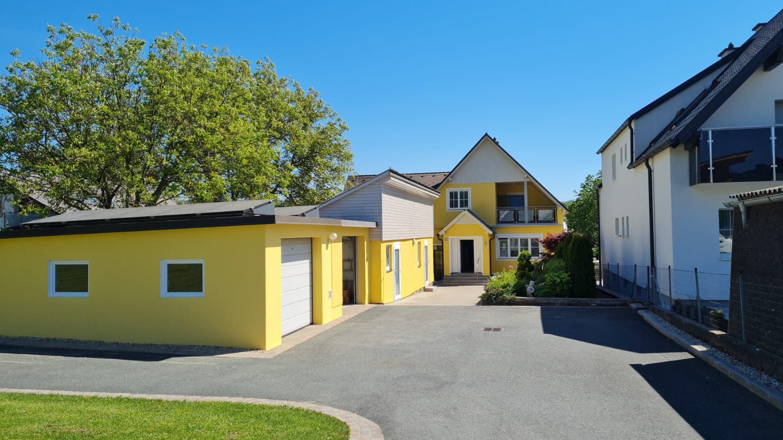 Ein gelbes Haus mit einer weißen Garage daneben