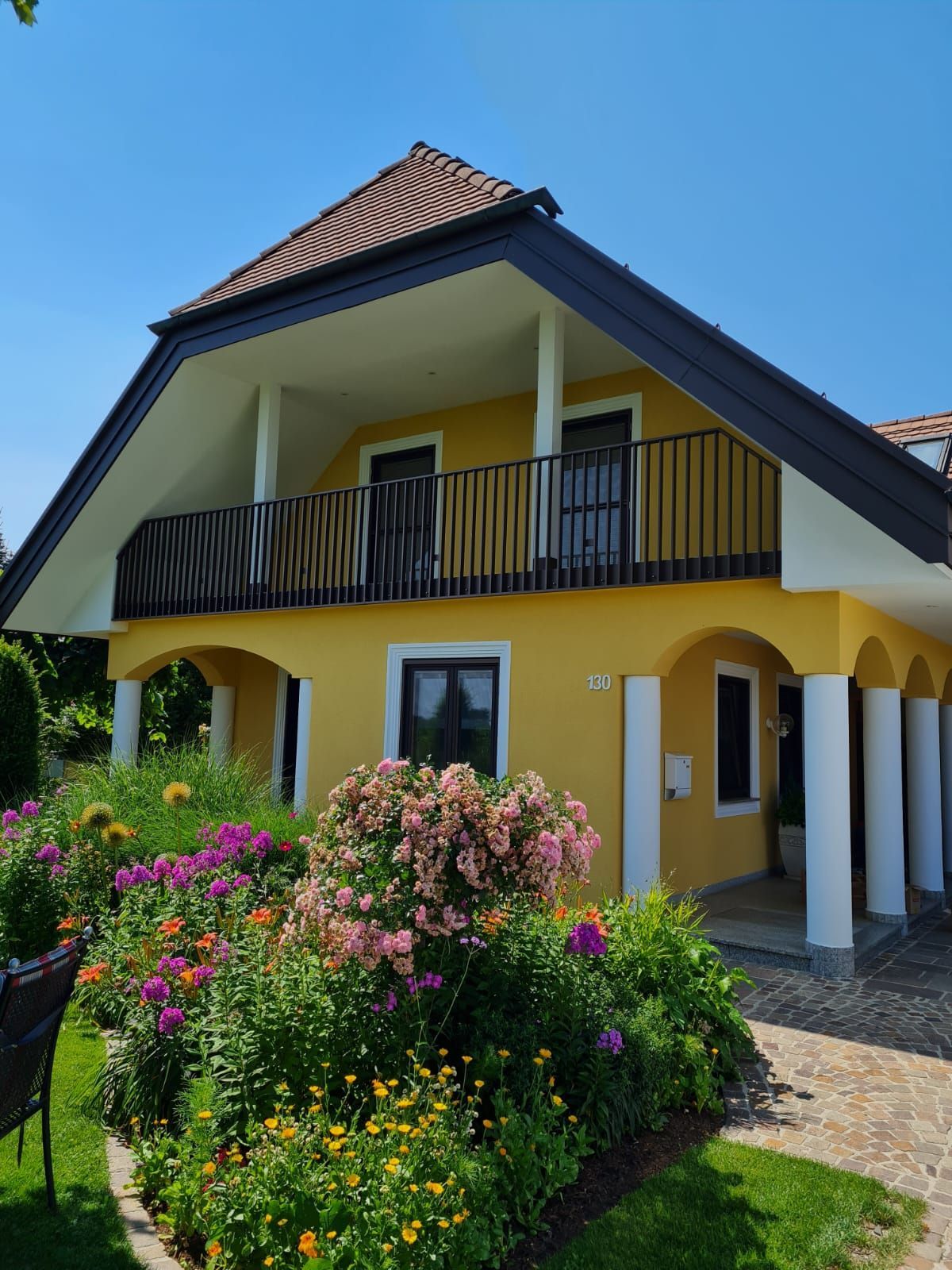 Ein gelbes Haus mit einem Balkon und Blumen davor