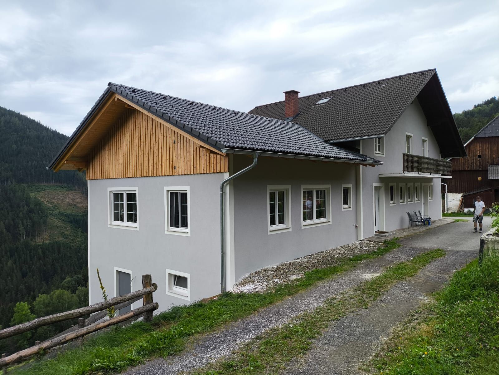 Auf einem Hügel steht ein großes weißes Haus mit Holzdach.