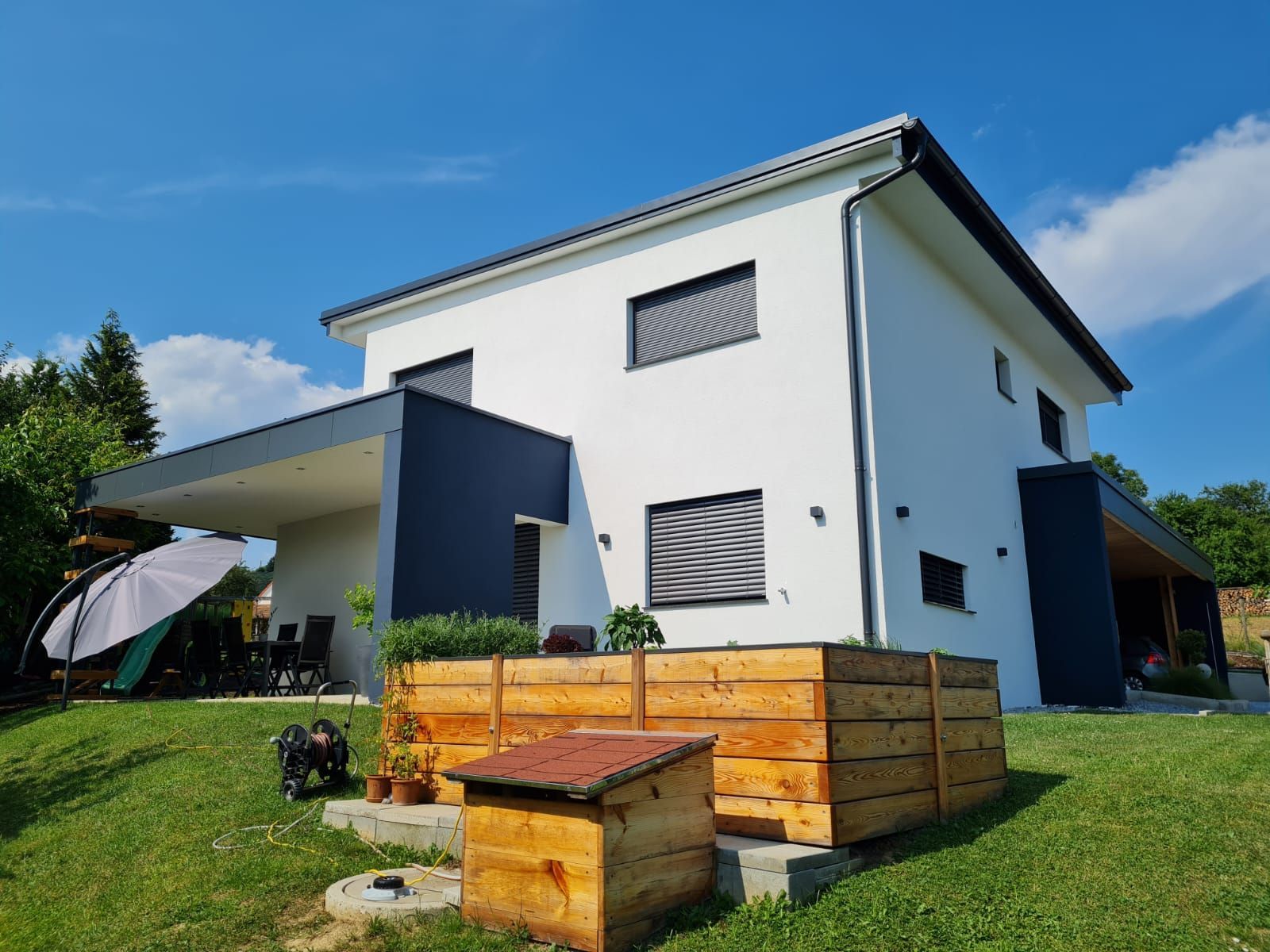 Ein weißes Haus mit einem Holzumrahmten Blumenbeet