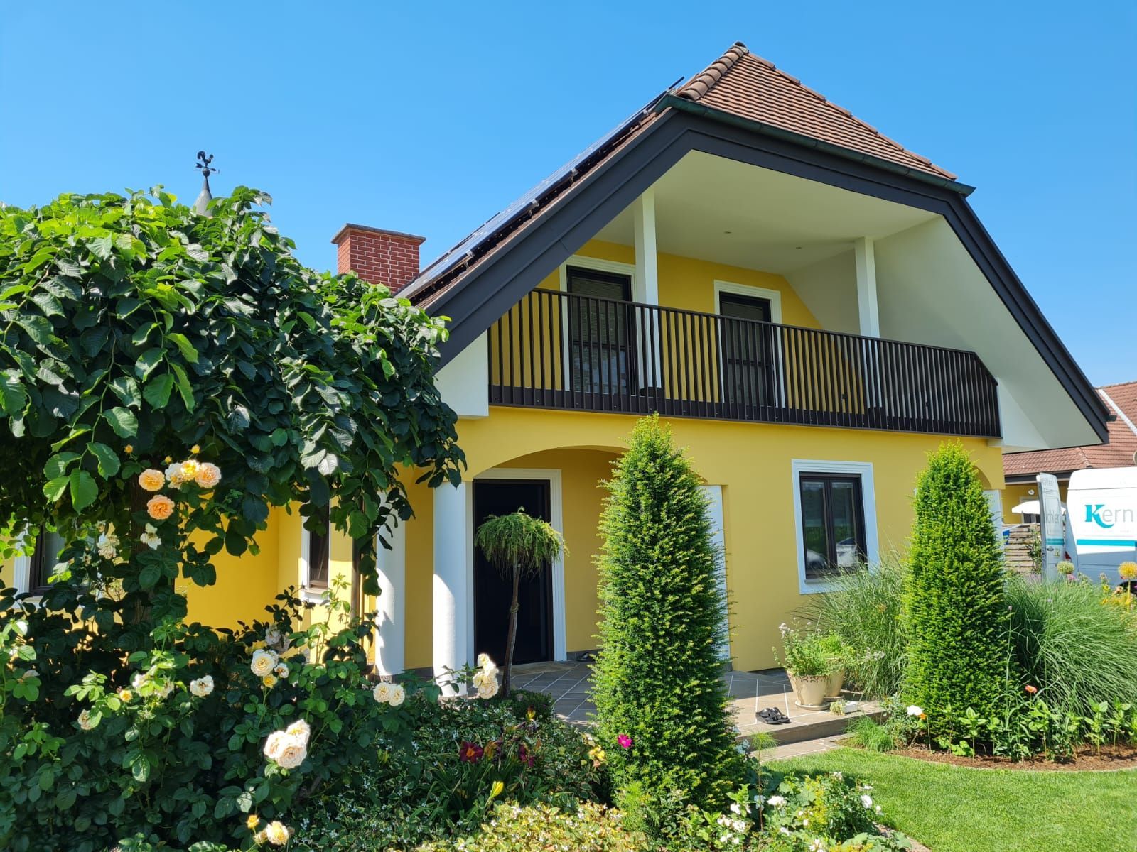Ein gelbes Haus mit einem Balkon und Blumen davor