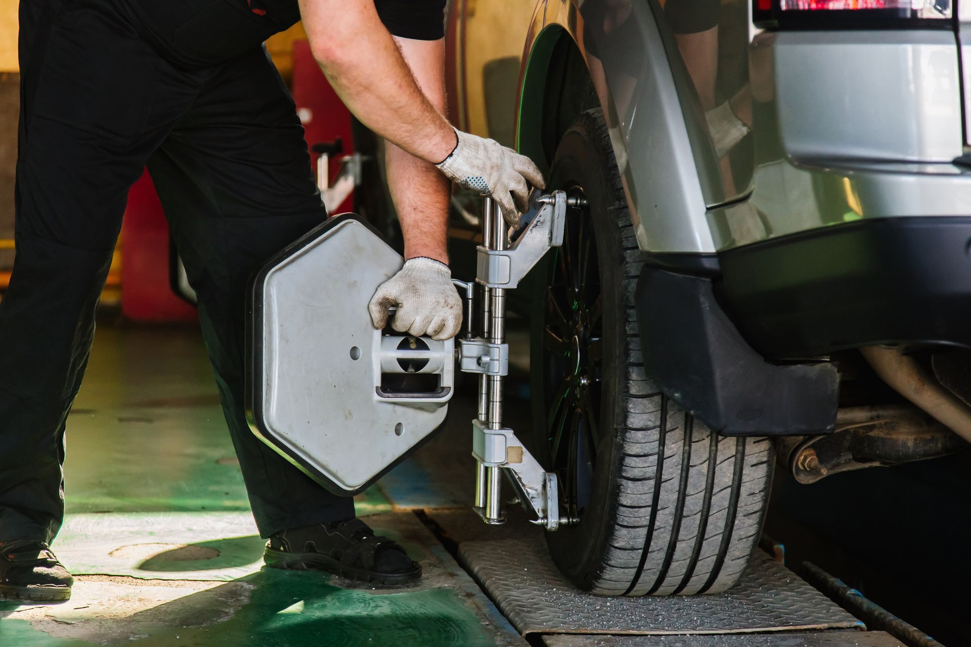 A man is adjusting a tire on a car in a garage.