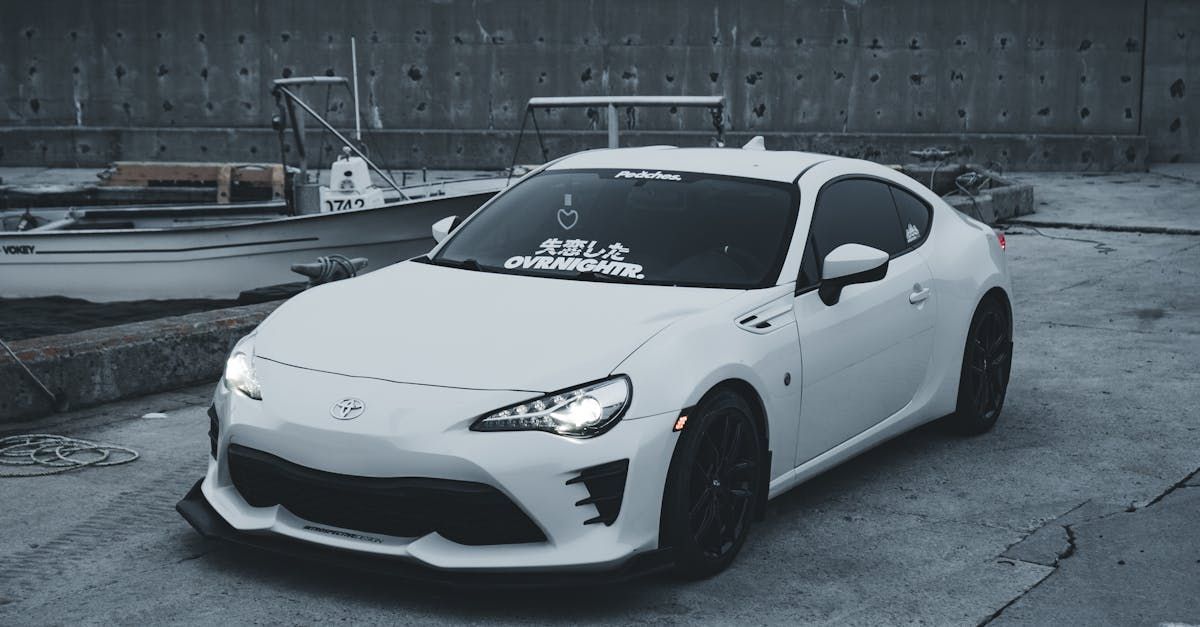 A white sports car is parked in a parking lot in front of a building.  | Automotive Specialists