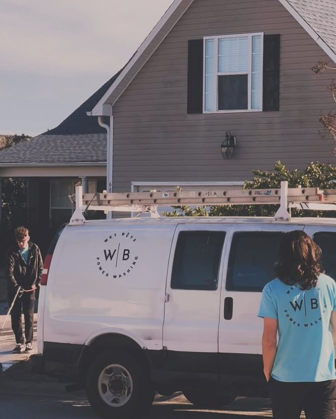 White service van parked in a driveway beside a house, with two people standing nearby.