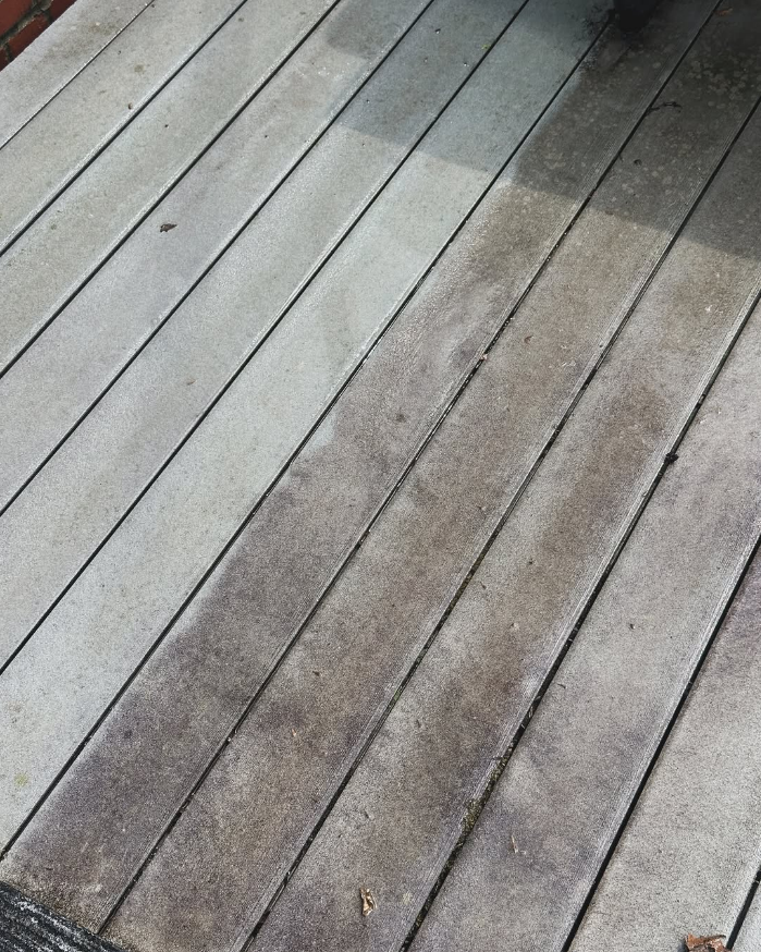 Weathered gray wooden deck boards with diagonal sunlight and shadow across the surface