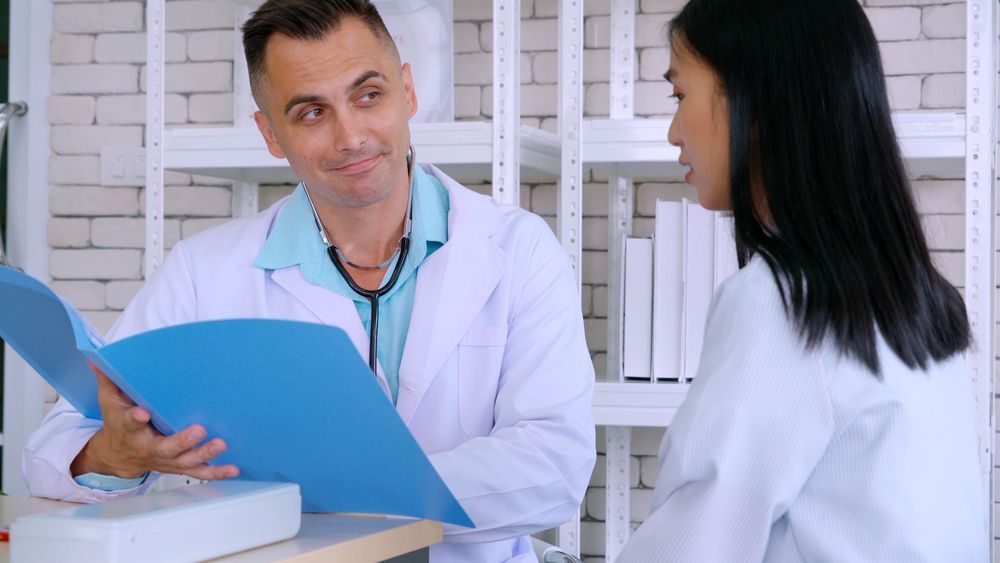 Un médico está hablando con un paciente mientras mira un portapapeles.