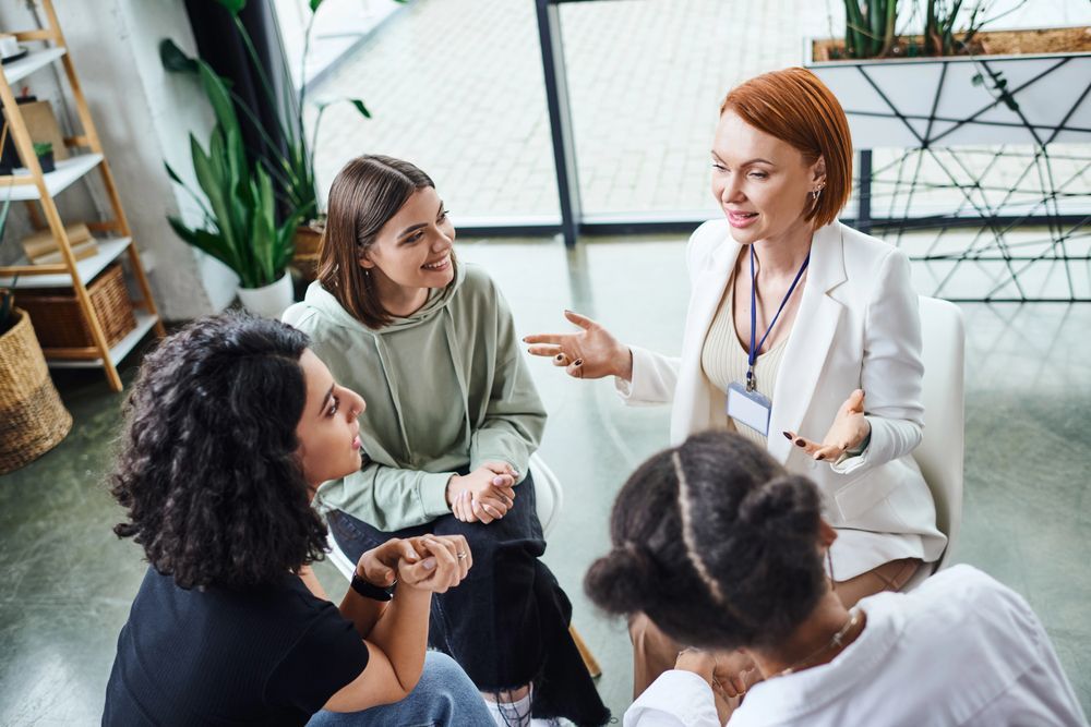 Un grupo de mujeres están sentadas en círculo hablando entre sí.