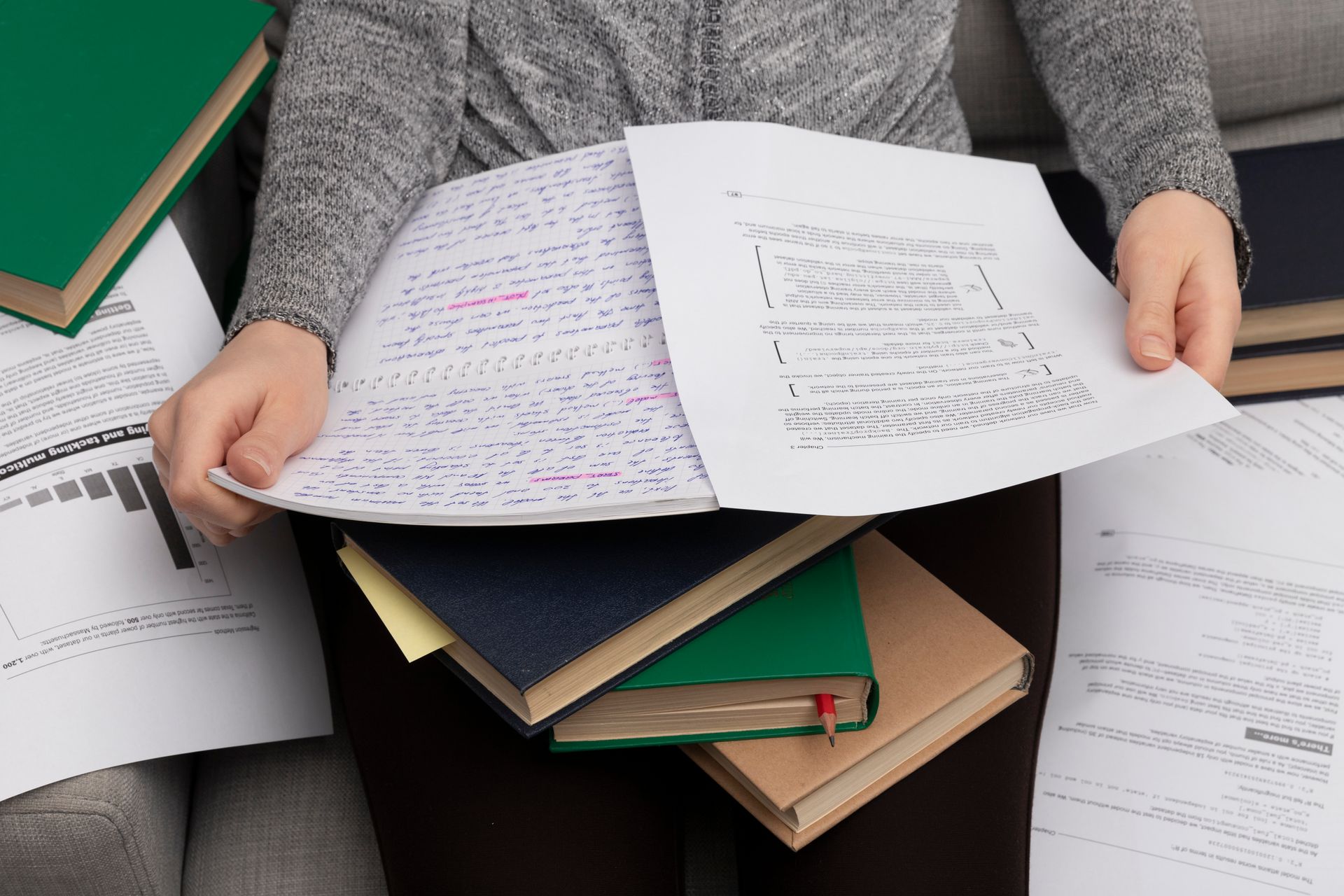Unas manos abren un sobre blanco sobre un escritorio de madera junto a un cuaderno negro y un bolígrafo verde.