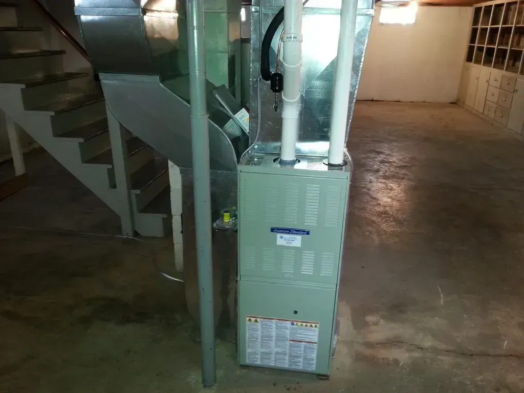 An air conditioner in a basement next to stairs
