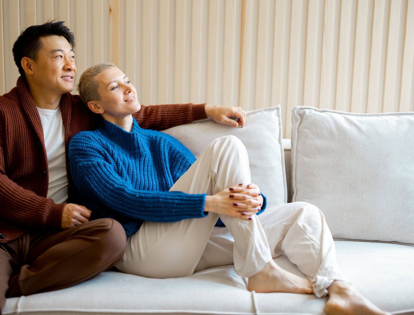 Couple on a couch, both looking up, smiling.