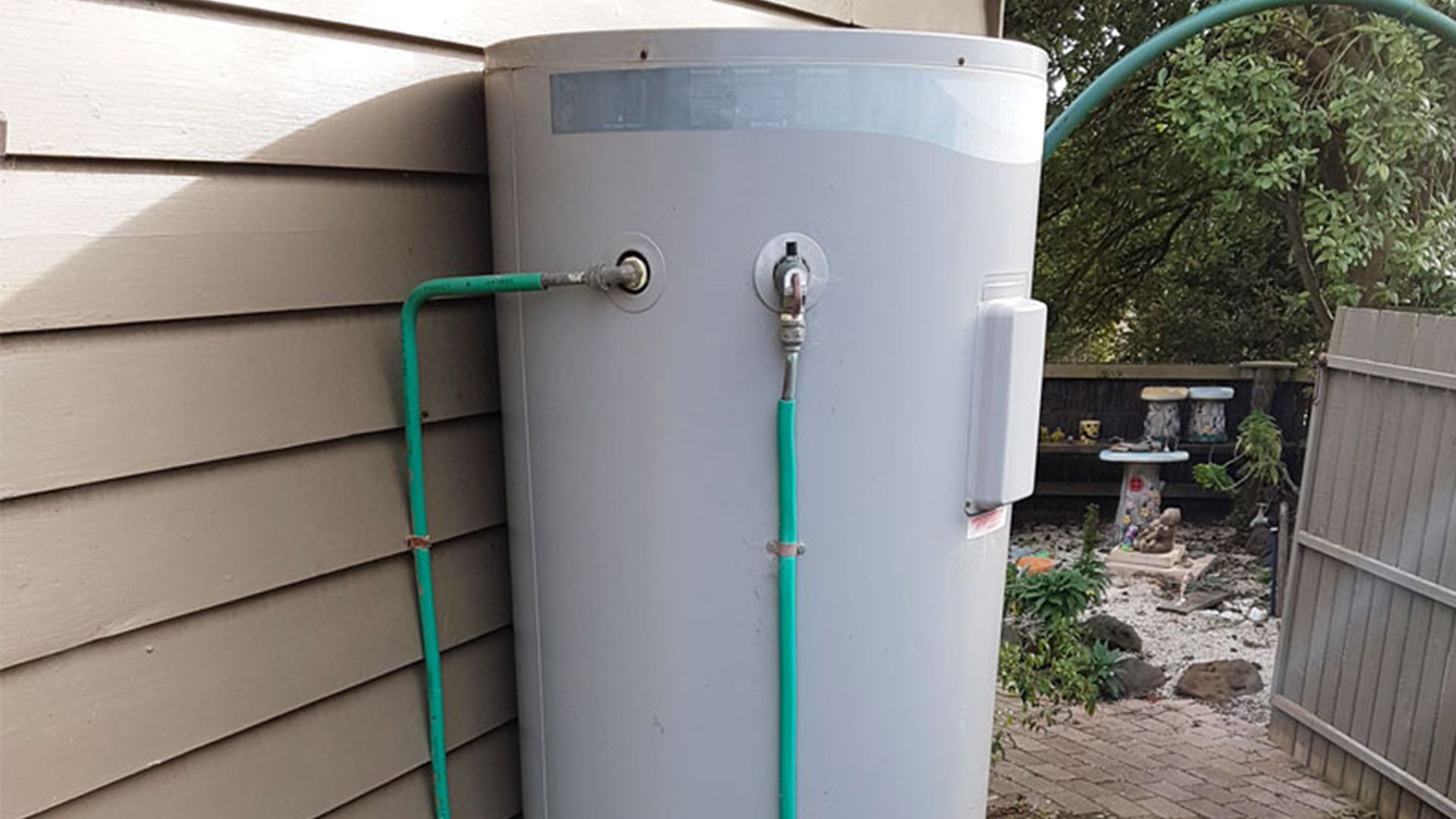 A large white water heater is attached to the side of a house.