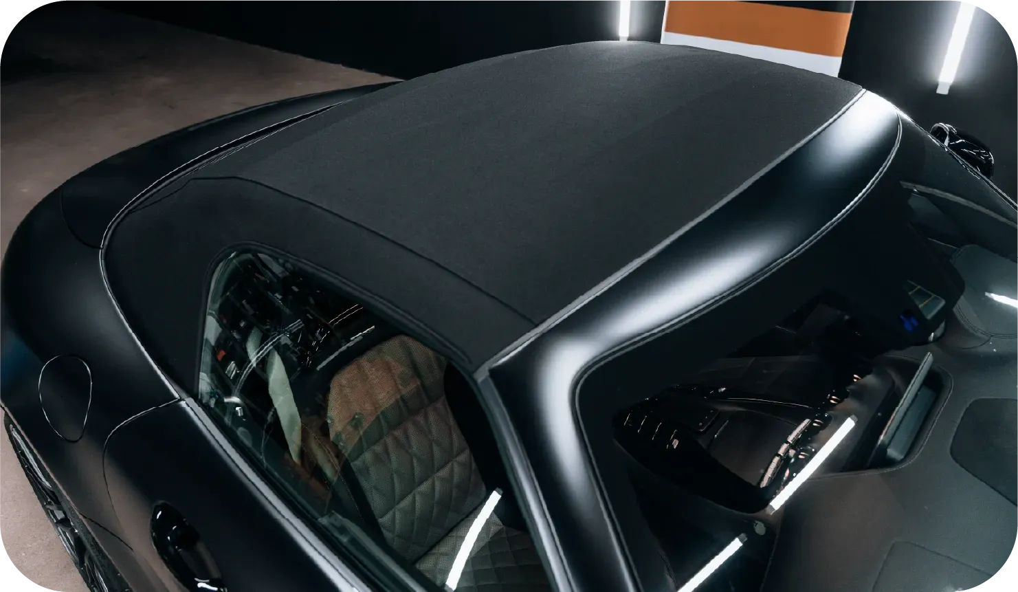 Black convertible car's roof from above, with interior visible through the windshield.