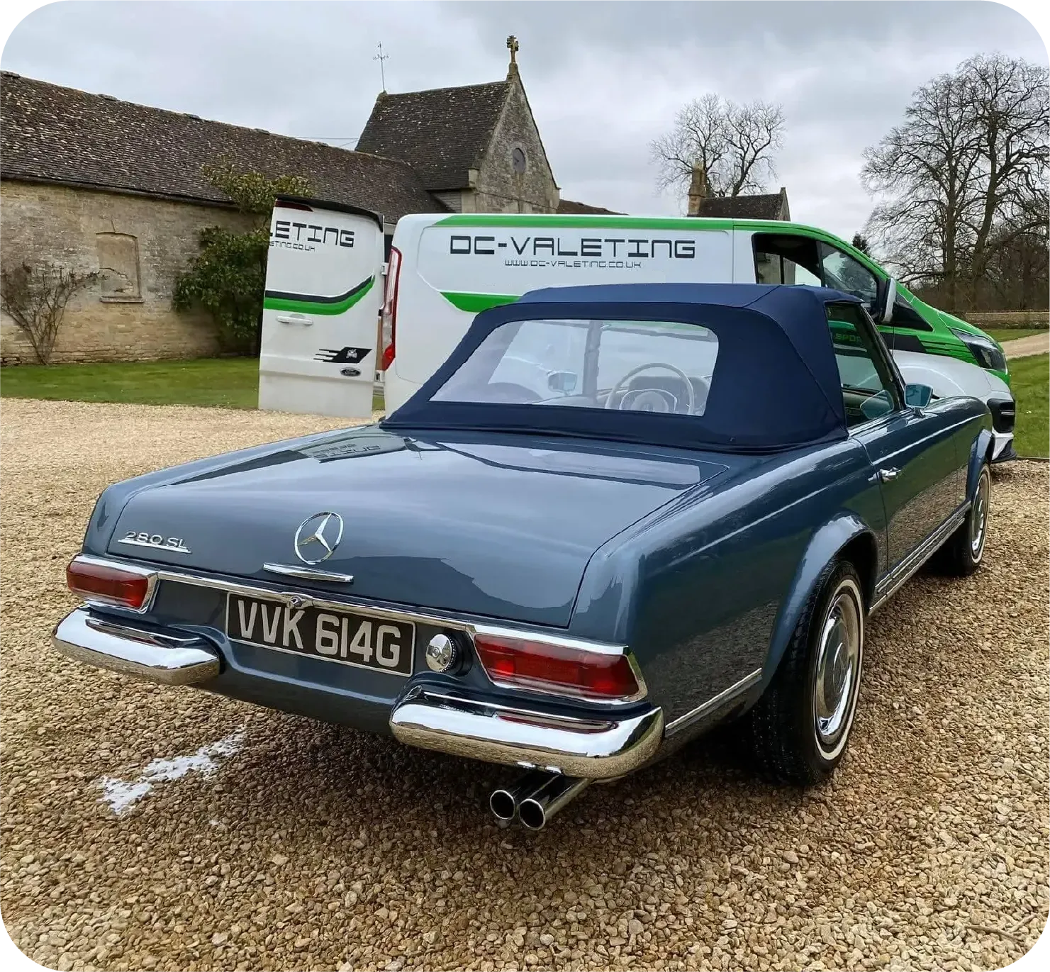 Classic blue Mercedes convertible parked in front of a white van labeled