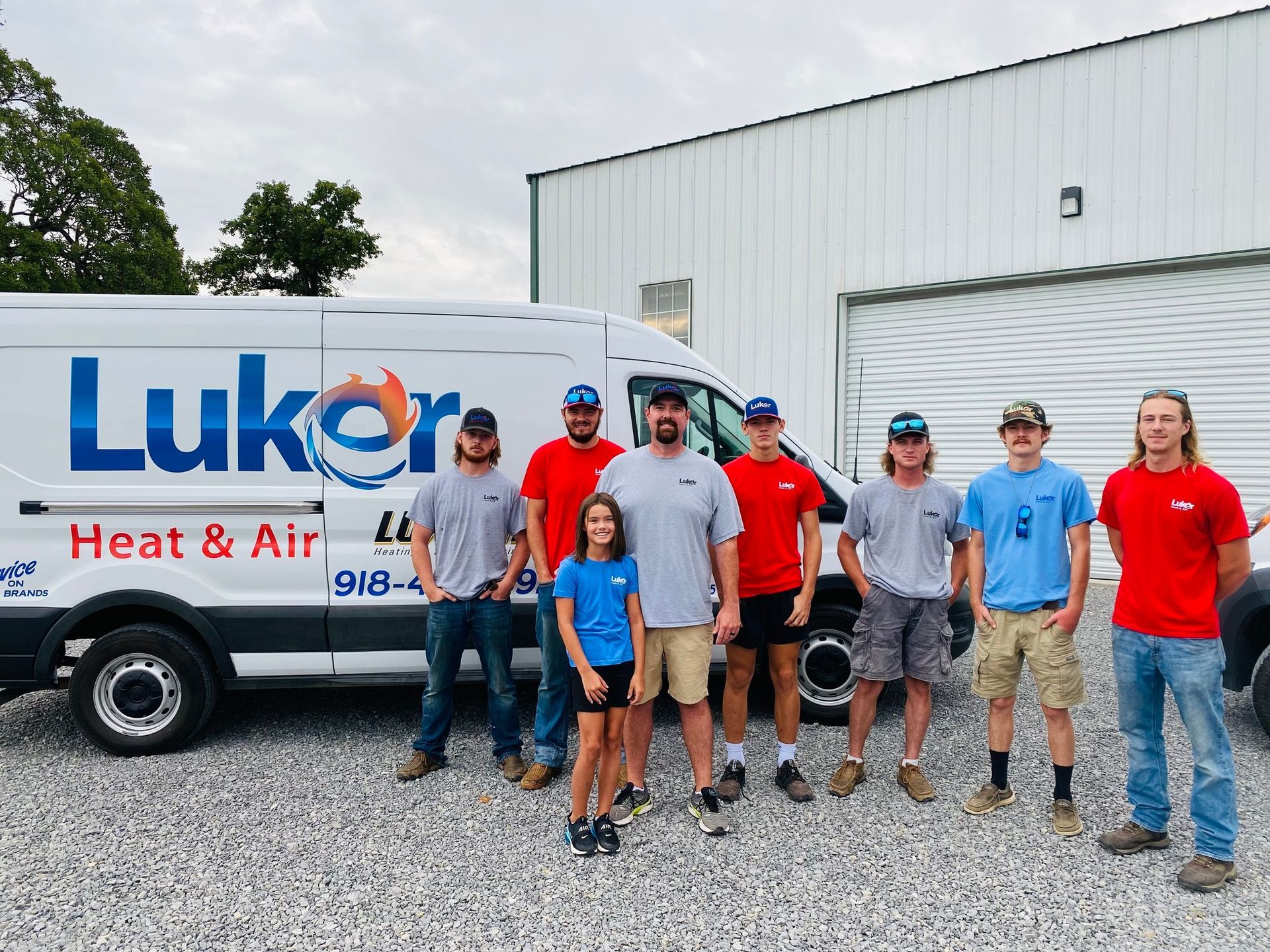 A group of people standing in front of a lukor heat and air van.