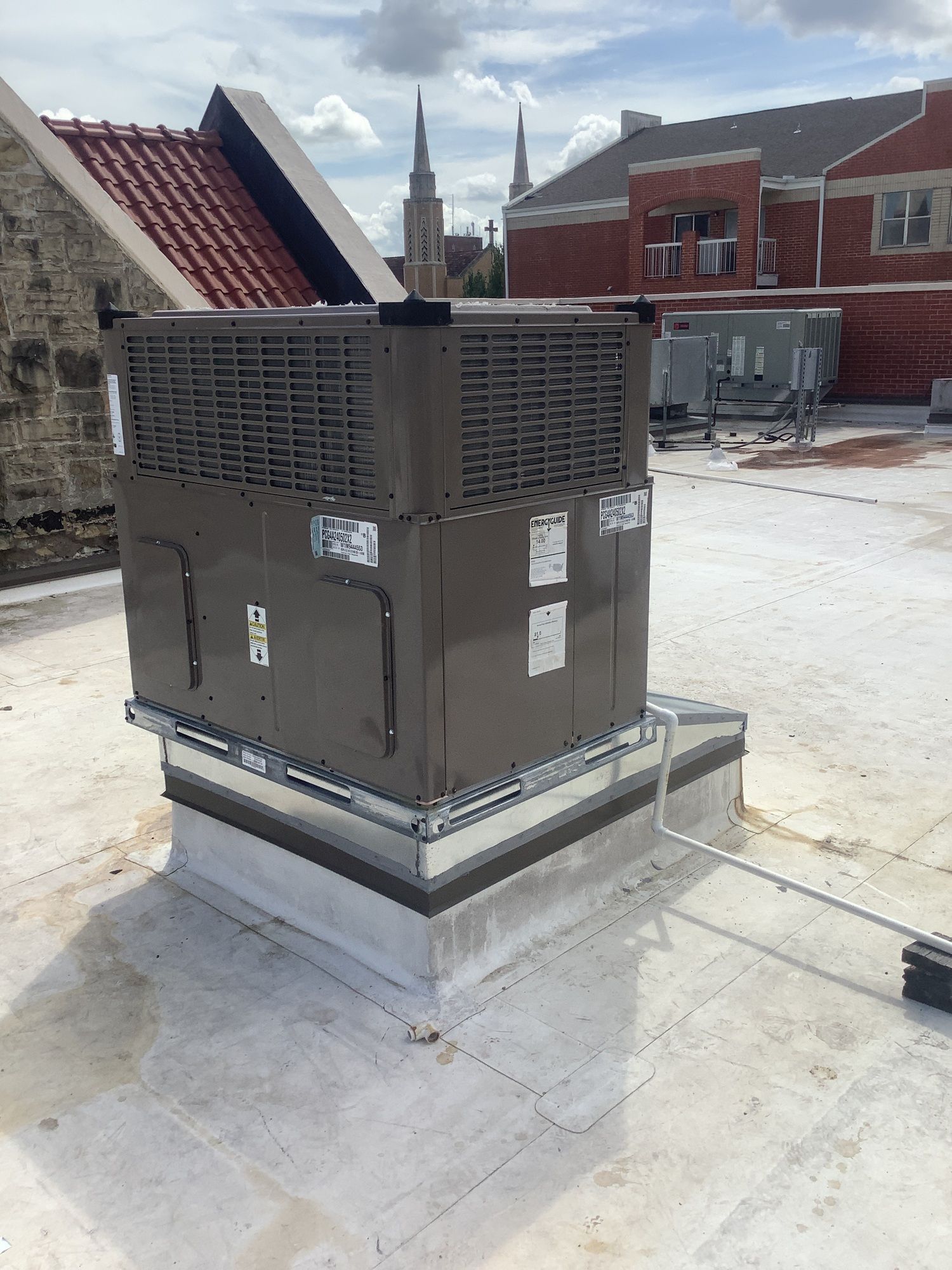 A large air conditioner is sitting on top of a white roof.