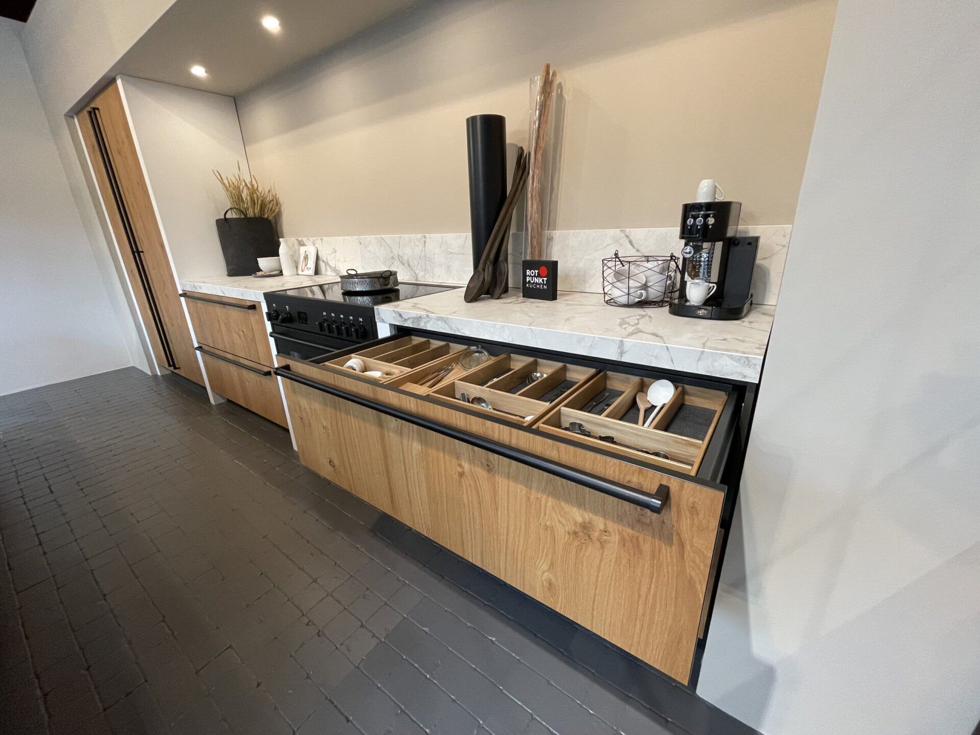 Een keuken met houten kasten en een marmeren aanrechtblad.